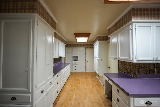 kitchen featuring white cabinetry, light hardwood / wood-style floors, and ornamental molding