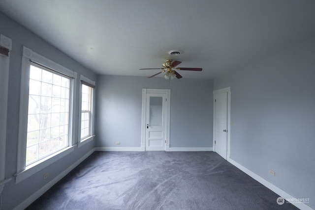 interior space featuring ceiling fan and dark carpet