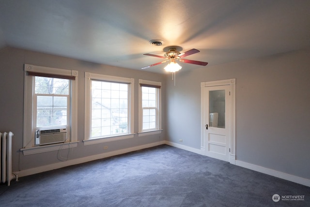 carpeted spare room featuring radiator, ceiling fan, and a wealth of natural light