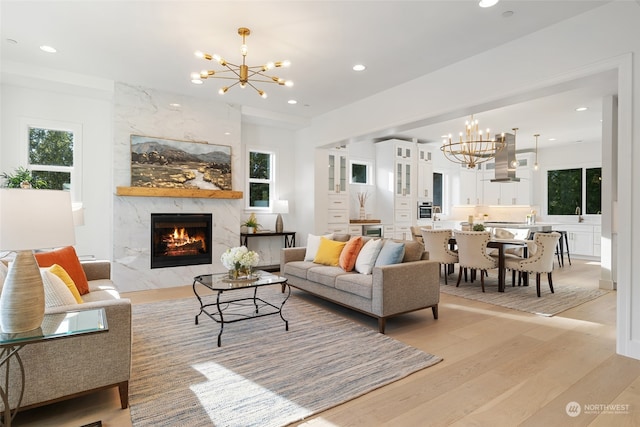 living room with an inviting chandelier, light wood-type flooring, and a premium fireplace