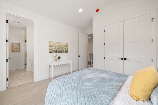 bedroom featuring light colored carpet, lofted ceiling, ensuite bathroom, a closet, and recessed lighting