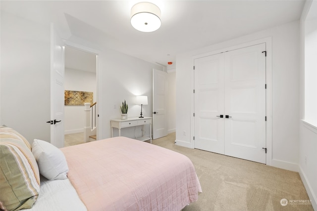 bedroom with light carpet, a closet, and baseboards