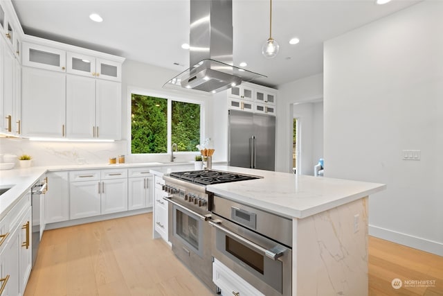 kitchen with a kitchen island, premium appliances, island exhaust hood, white cabinetry, and light hardwood / wood-style floors