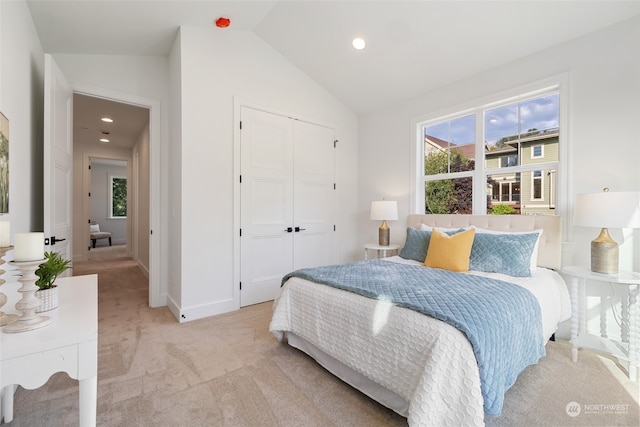 bedroom with vaulted ceiling, a closet, and light colored carpet