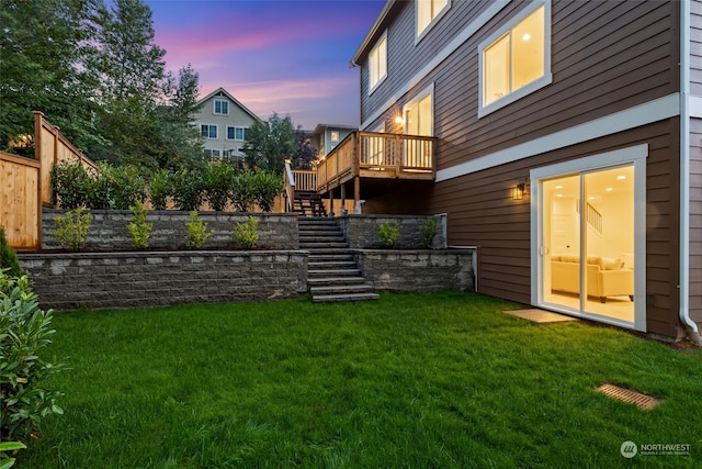 yard at dusk with a deck, stairway, and fence