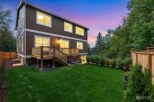 back house at dusk featuring a yard and a wooden deck