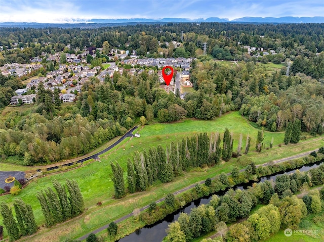 drone / aerial view featuring a forest view and a water and mountain view