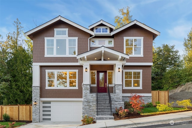 craftsman-style house with driveway, stone siding, an attached garage, and fence