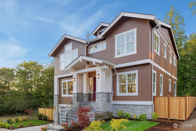 craftsman-style house with stone siding and fence