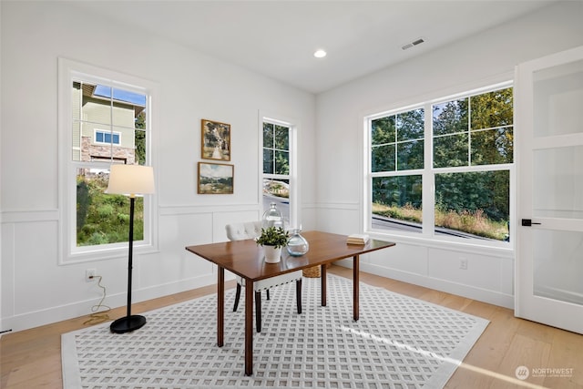 office space featuring light wood finished floors, recessed lighting, visible vents, and a decorative wall