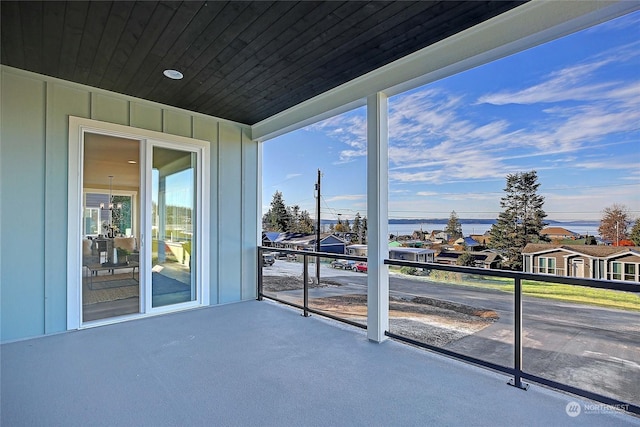 sunroom / solarium with a chandelier, a water view, and wooden ceiling