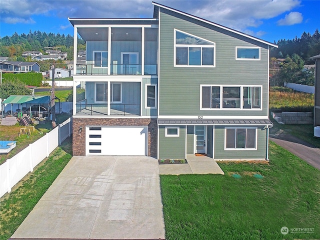 view of front facade featuring a balcony, a front lawn, and a garage