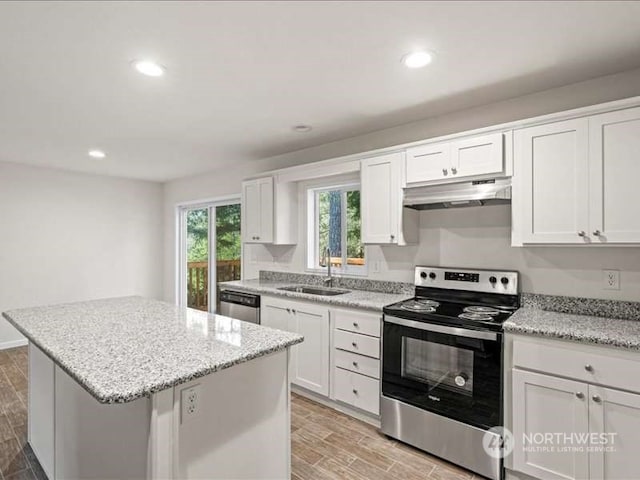 kitchen featuring sink, white cabinets, stainless steel appliances, light stone countertops, and a center island