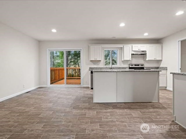 kitchen featuring stove, white cabinets, and a wealth of natural light