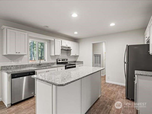 670 E Wilson Way, Grapeview, WA 98546 - kitchen with appliances with stainless steel finishes, a sink, wood finished floors, a center island, and white cabinetry