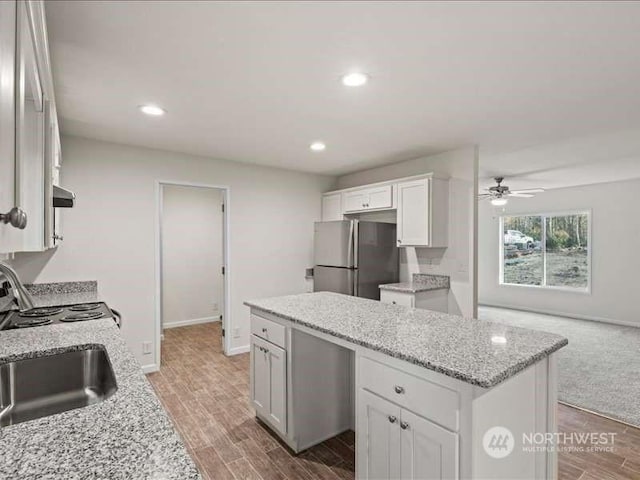 670 E Wilson Way, Grapeview, WA 98546 - kitchen featuring freestanding refrigerator, a kitchen island, a ceiling fan, exhaust hood, and white cabinetry