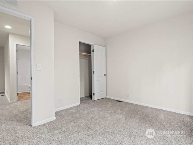 unfurnished bedroom with a closet and light colored carpet