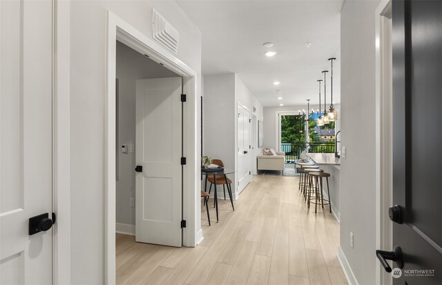 corridor featuring an inviting chandelier and light wood-type flooring