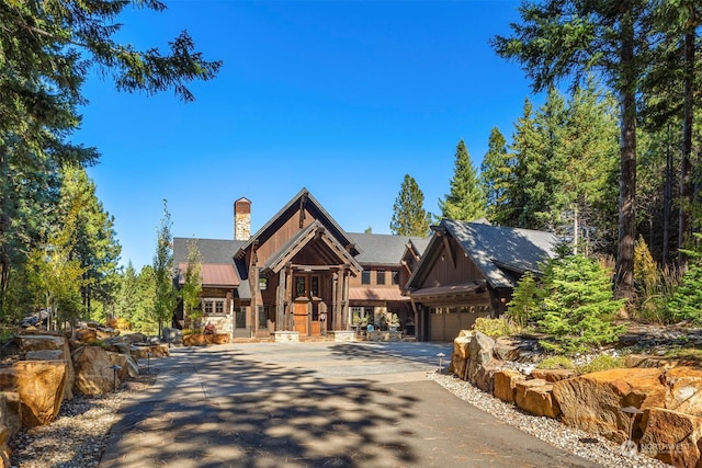 view of front of property featuring board and batten siding, an attached garage, metal roof, and driveway