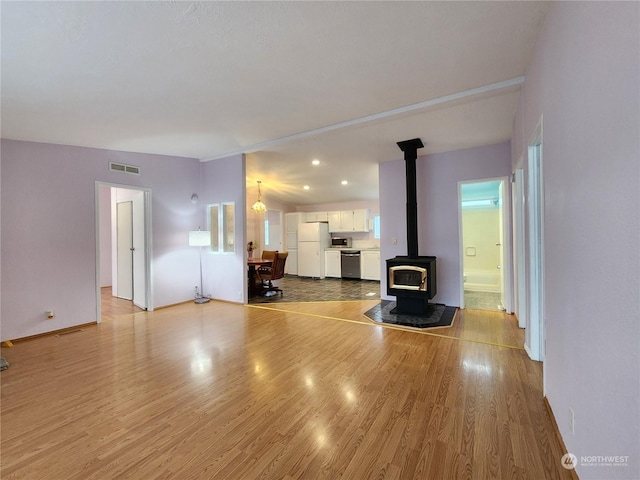 unfurnished living room with a wood stove and light hardwood / wood-style flooring