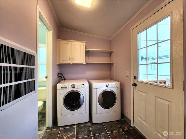 washroom featuring a healthy amount of sunlight, crown molding, washing machine and clothes dryer, and cabinets