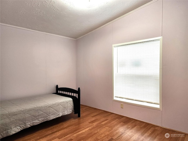 bedroom featuring a textured ceiling, hardwood / wood-style floors, and crown molding