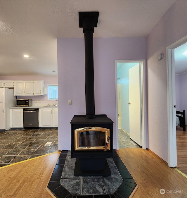 room details featuring sink, stainless steel appliances, a wood stove, and hardwood / wood-style floors