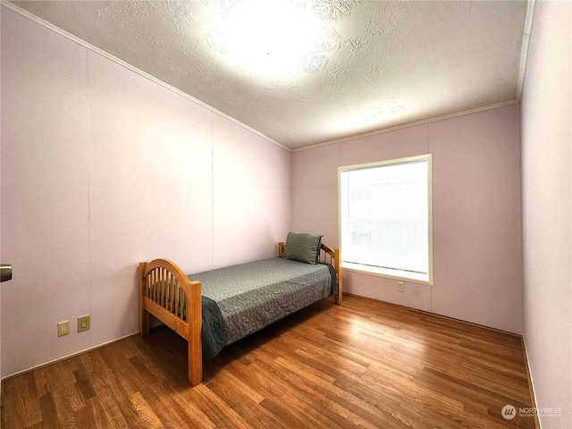 bedroom with a textured ceiling, crown molding, and hardwood / wood-style floors