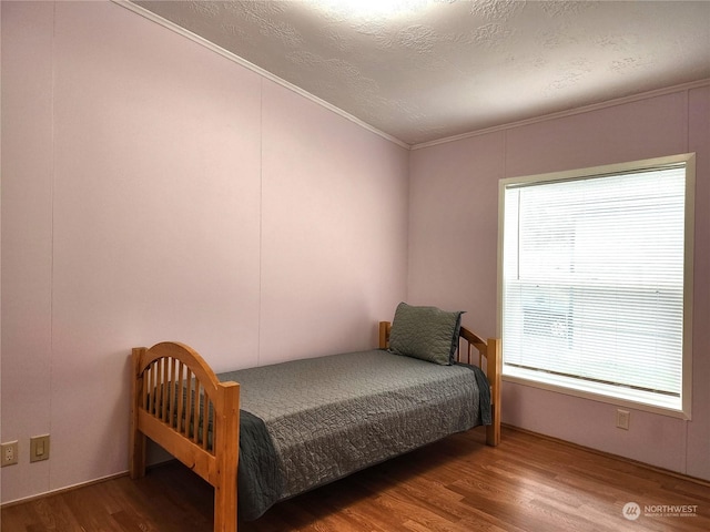 bedroom featuring a textured ceiling, hardwood / wood-style floors, and crown molding