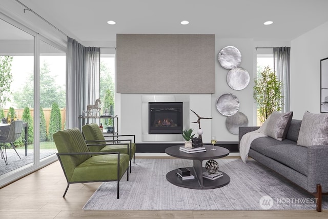 living area with recessed lighting, wood finished floors, and a glass covered fireplace