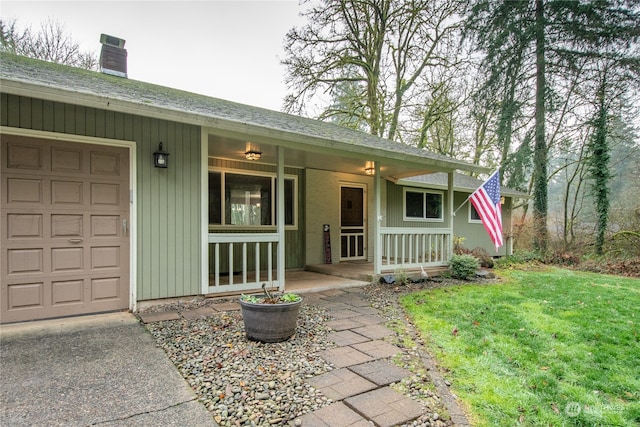 view of front of home featuring covered porch, a garage, and a front yard