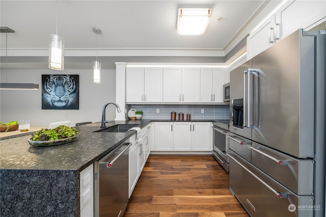 kitchen with appliances with stainless steel finishes, decorative light fixtures, dark hardwood / wood-style flooring, sink, and white cabinetry