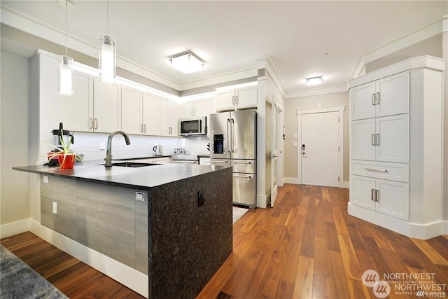 kitchen with dark wood-type flooring, sink, stainless steel appliances, dark stone countertops, and pendant lighting