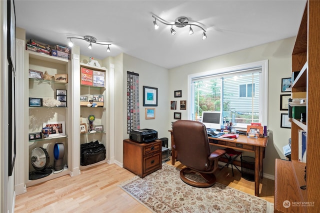 office with light hardwood / wood-style floors and rail lighting