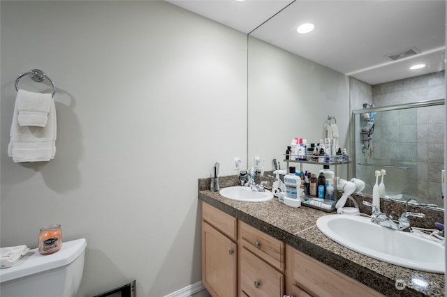 bathroom featuring dual vanity, toilet, and an enclosed shower