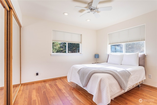 bedroom with a closet, hardwood / wood-style flooring, multiple windows, and ceiling fan