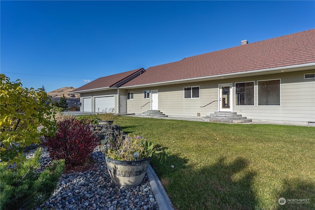 rear view of property featuring a lawn and a garage