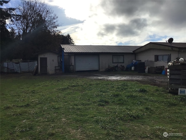 rear view of property with a storage shed, a garage, and a lawn