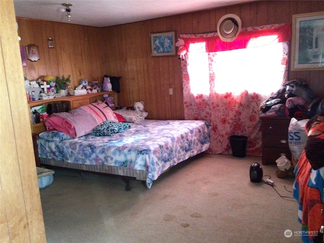 carpeted bedroom featuring wood walls