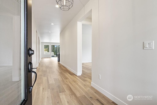 hall featuring light wood-type flooring and an inviting chandelier