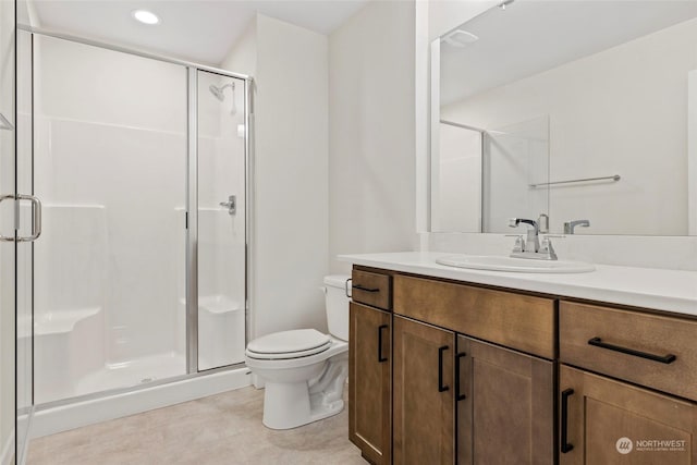 bathroom featuring vanity, a shower with shower door, and toilet