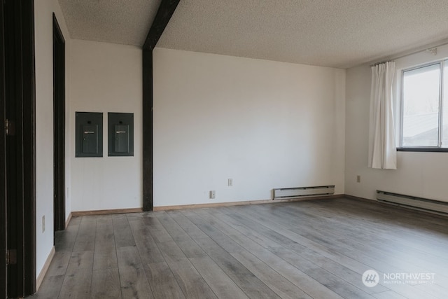 spare room with a baseboard radiator, a textured ceiling, and light wood-type flooring