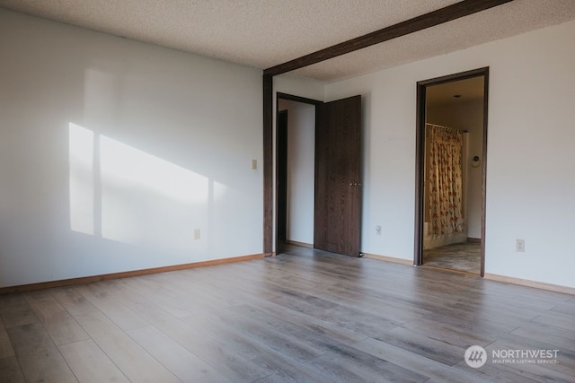 spare room featuring light hardwood / wood-style floors and a textured ceiling