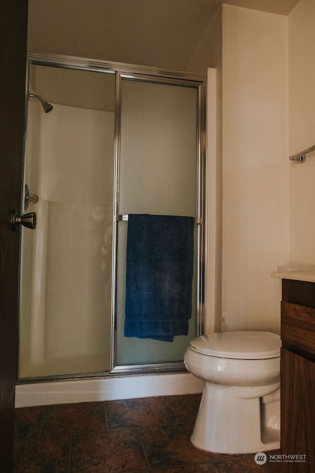 bathroom with tile floors, toilet, vanity, and a shower with shower door