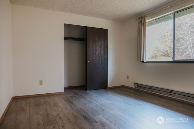 unfurnished bedroom with dark hardwood / wood-style flooring, a textured ceiling, a closet, and multiple windows