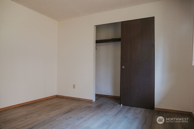 unfurnished bedroom featuring a textured ceiling, light wood-type flooring, and a closet