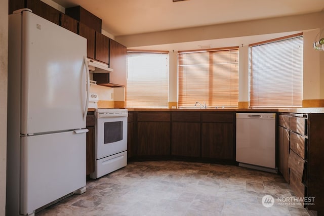 kitchen with dark brown cabinetry, tile flooring, white appliances, and sink