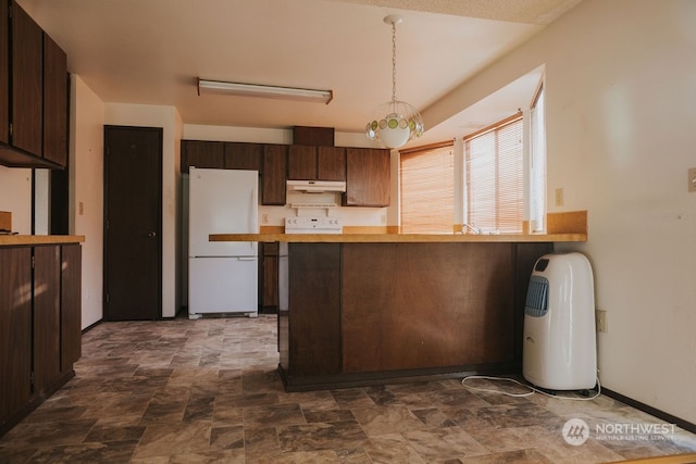 kitchen with white fridge, hanging light fixtures, dark tile flooring, and dark brown cabinetry