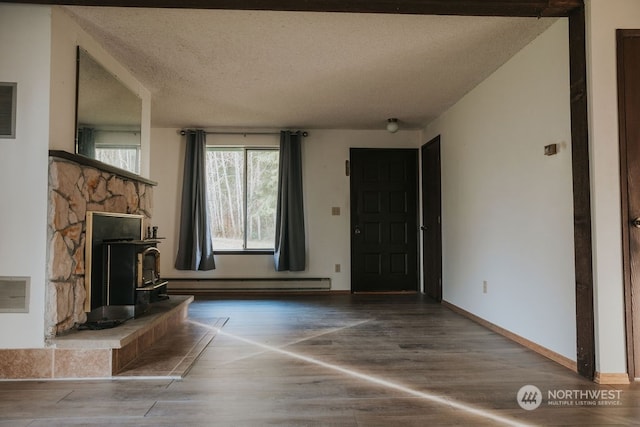 unfurnished living room with dark hardwood / wood-style flooring, a wood stove, a textured ceiling, and a baseboard radiator