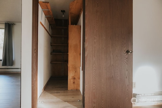 hall featuring a baseboard radiator and light hardwood / wood-style flooring